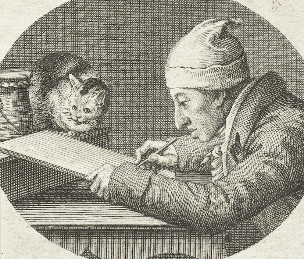 A man wearing a cap leans over a desk, deeply focused on his drawing. Next to him, a small cat sits with its paws close together, appearing to watch him work with curiosity and interest.