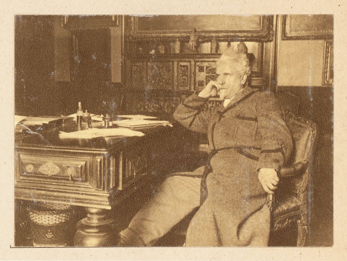 Photograph of a man sitting in a chair in a contemplative pose