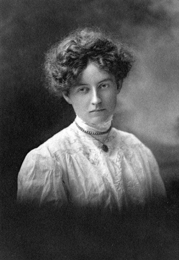 Portrait photograph of a young woman with curly dark hair wearing a white high-necked lace blouse and a delicate choker necklace with pendant.