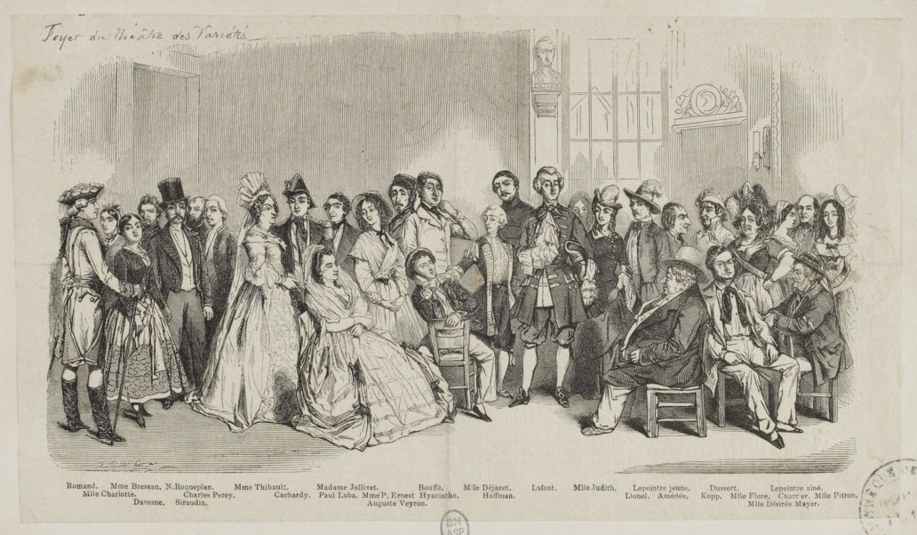 A group portrait of actors seated and standing with labels identifying individuals