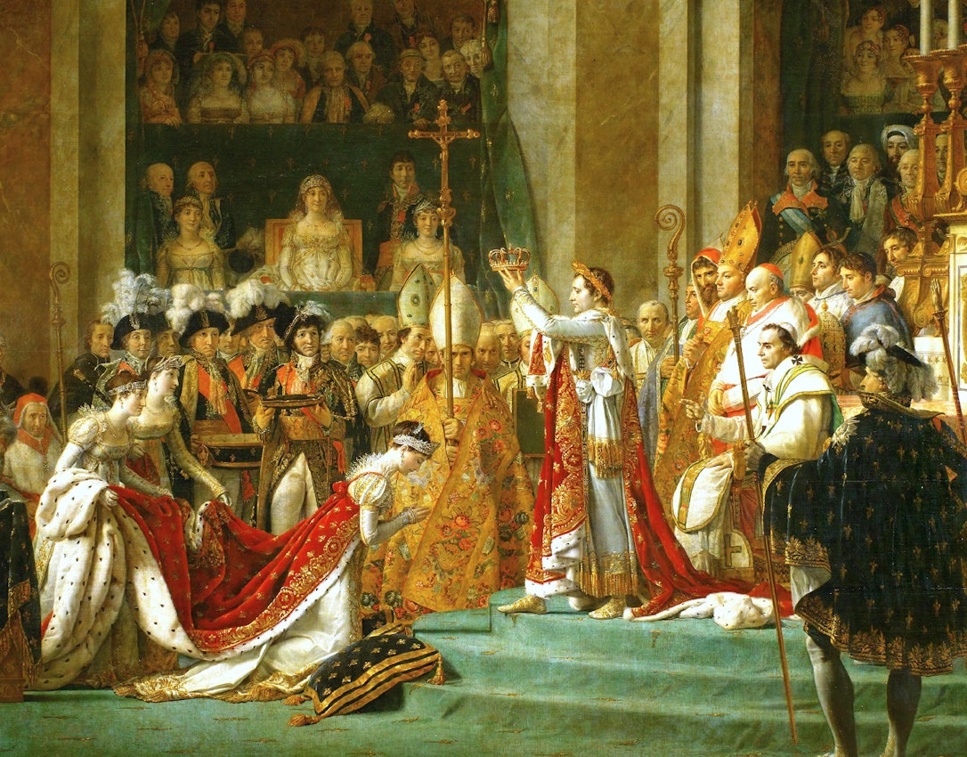 The painting captures a formal event. Central figures are adorned with crowns and lavish robes, holding scepters, surrounded by onlookers in equally rich attire. Napoleon holds a crown aloft in the center.
