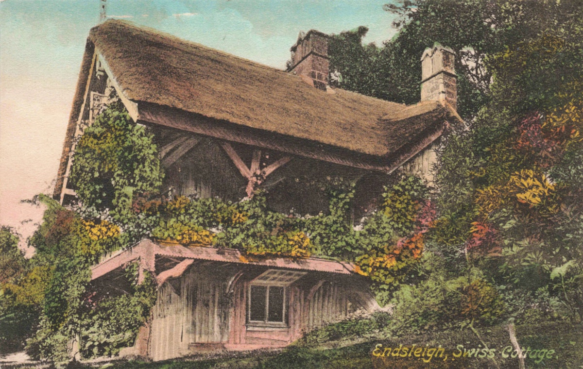 A thatched roof cottage with heavy foliage growing on its walls