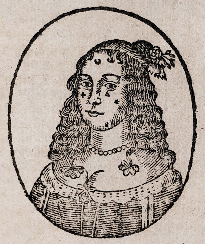 Black and white print of a person with long curly hair wearing a pearl necklace and ornate clothing within an oval frame.