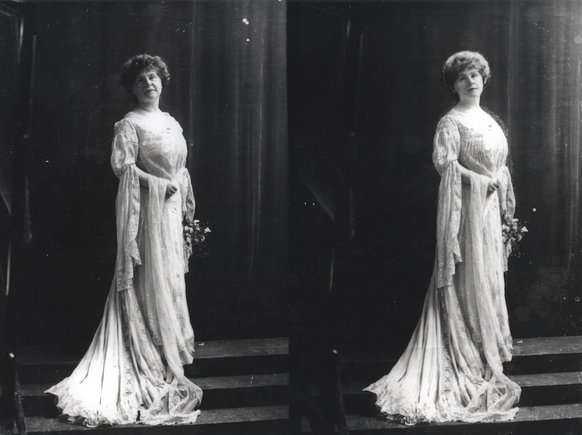 Marie Corelli standing in formal dress looking at the camera in a photography studio