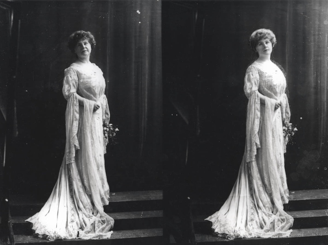 Marie Corelli standing in formal dress looking at the camera in a photography studio