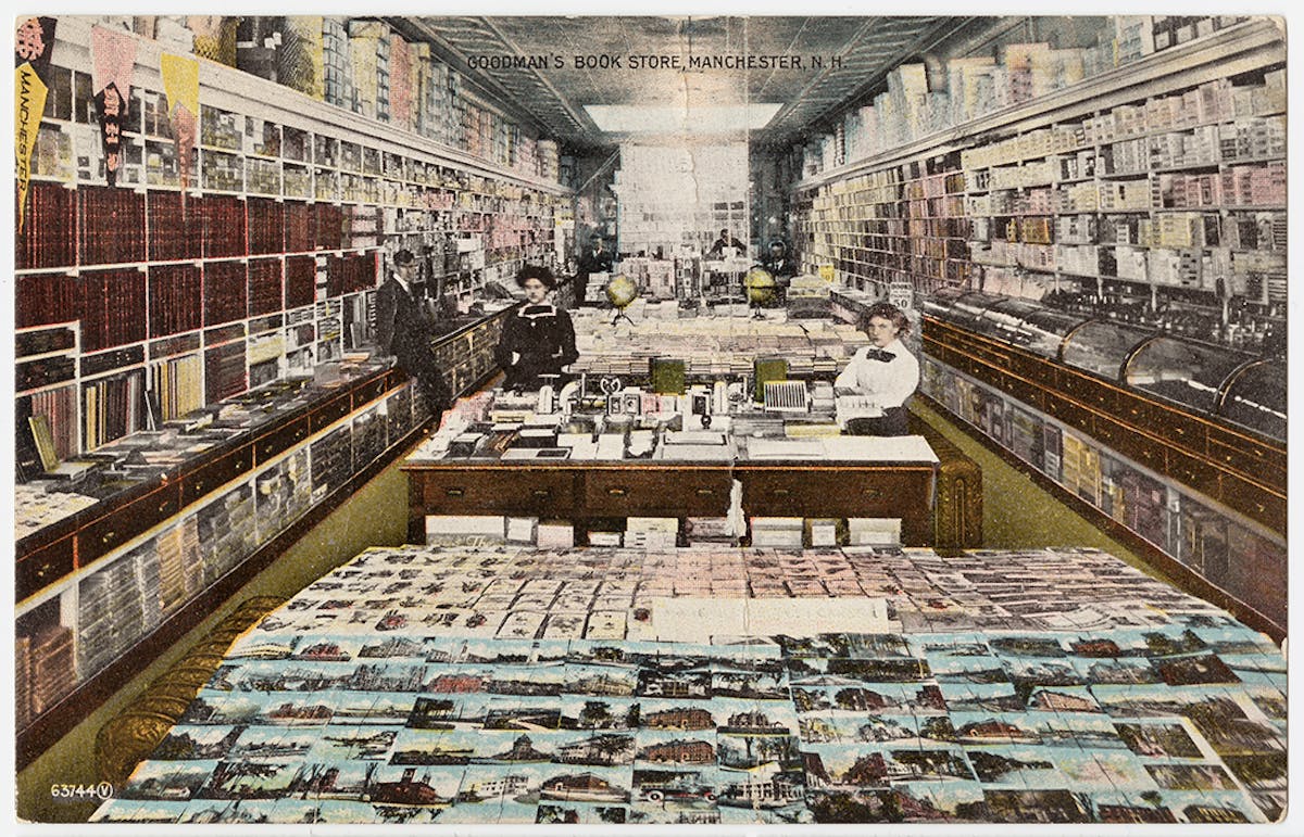 Goodman's Book Store in Manchester, N.H., featuring a spacious interior packed with books and postcards. The tables and shelves are overflowing with organized stacks of books and postcards, creating a bustling and well-stocked environment.