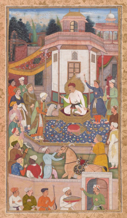 Miniature painting depicting a court scene with a central figure in white robes and red turban seated on a platform, surrounded by attendants, courtiers, and musicians in colorful attire.