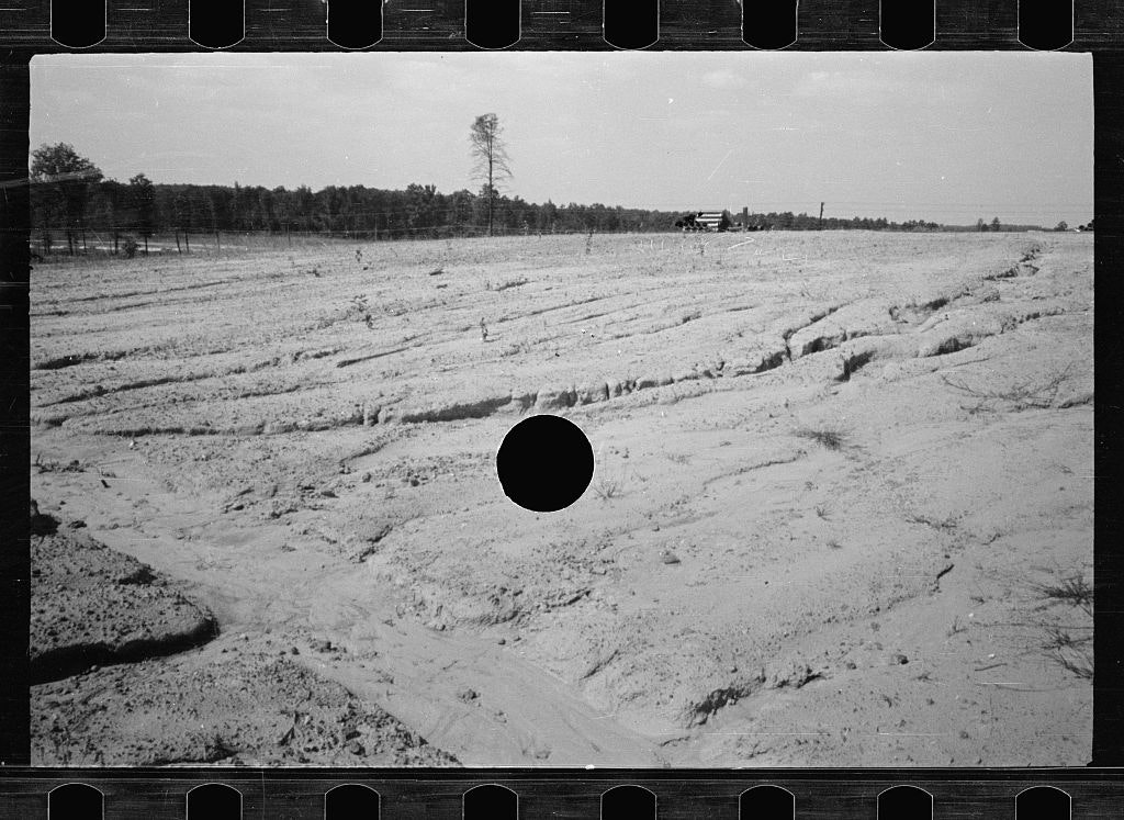 black and white photo of a dry field with a black hole in the centre