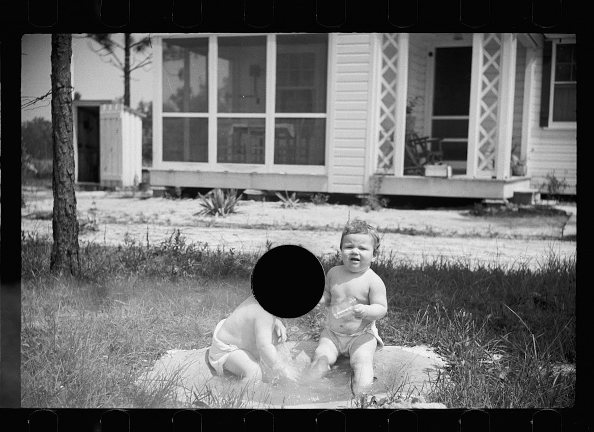 two babies in a garden, one of whose head is entirely obscured by the punctured hole