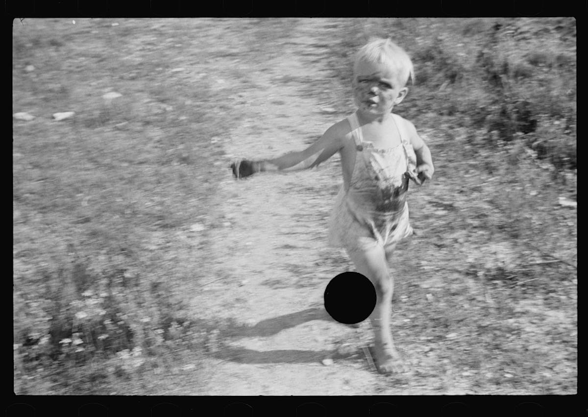 grubby boy in dungarees prancing, punctured hole where his legs meet his shadow