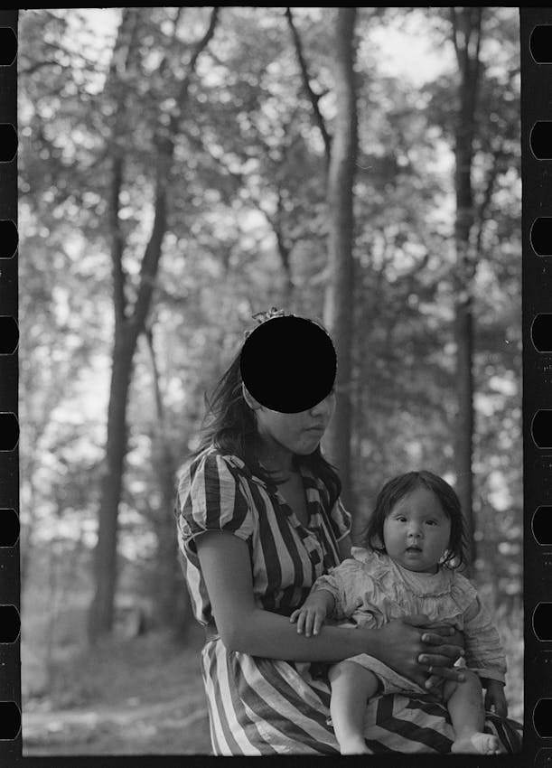 young native american mother sat with child on her lap, the punctured hole directly obscuring the top part of her head