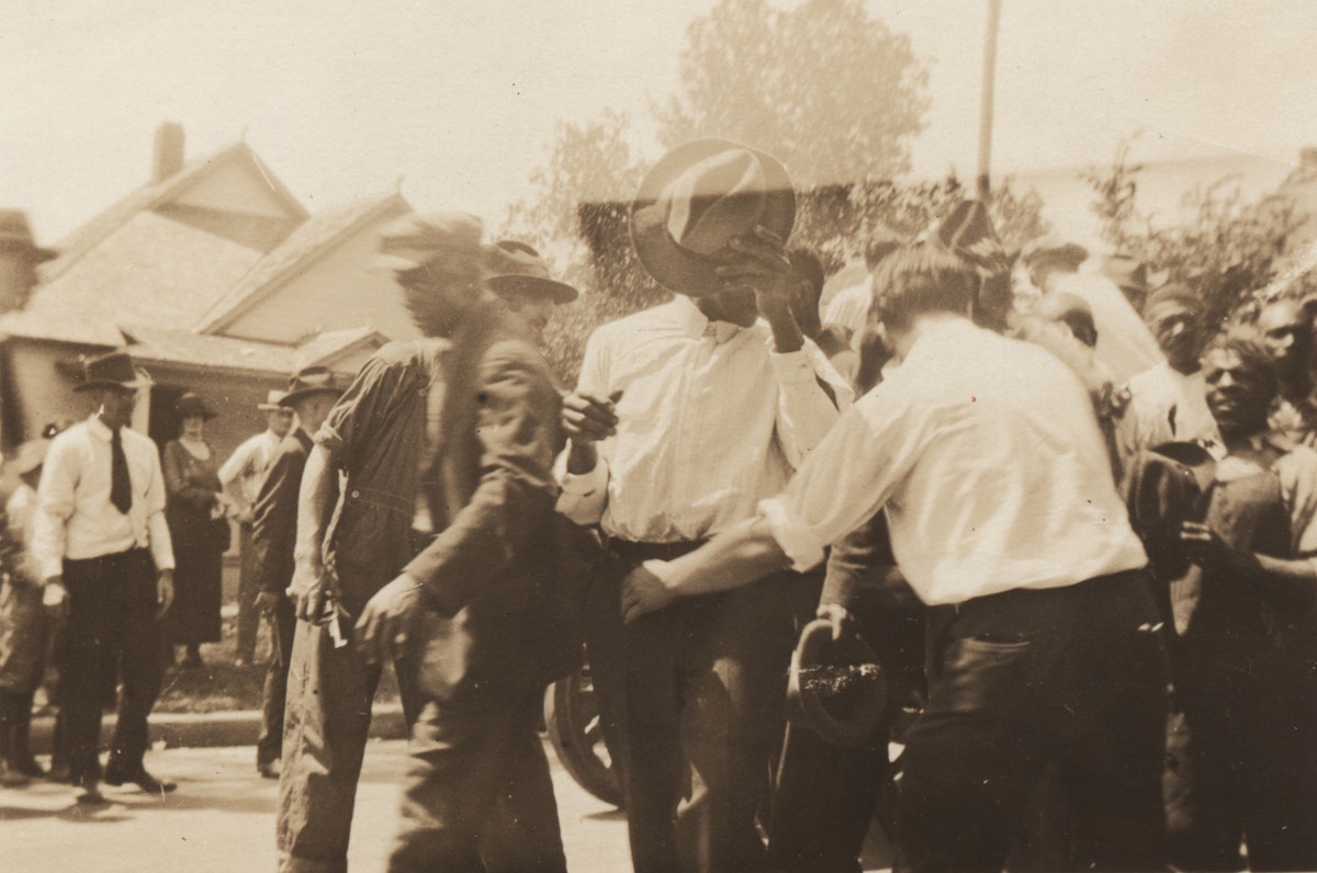 Group of Black men pushed together and led past white onlookers